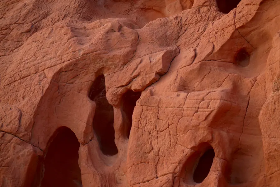 A close-up photo of red sandstone at Valley of Fire State Park, carved into smooth hollows and arches with fine cracks across the surface
